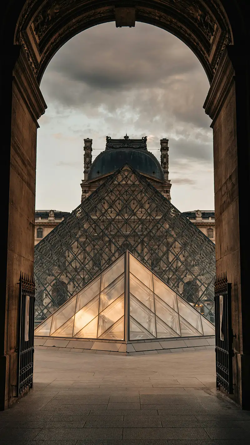 Reisebericht Paris: Blick auf die Louvre-Pyramide durch den historischen Torbogen