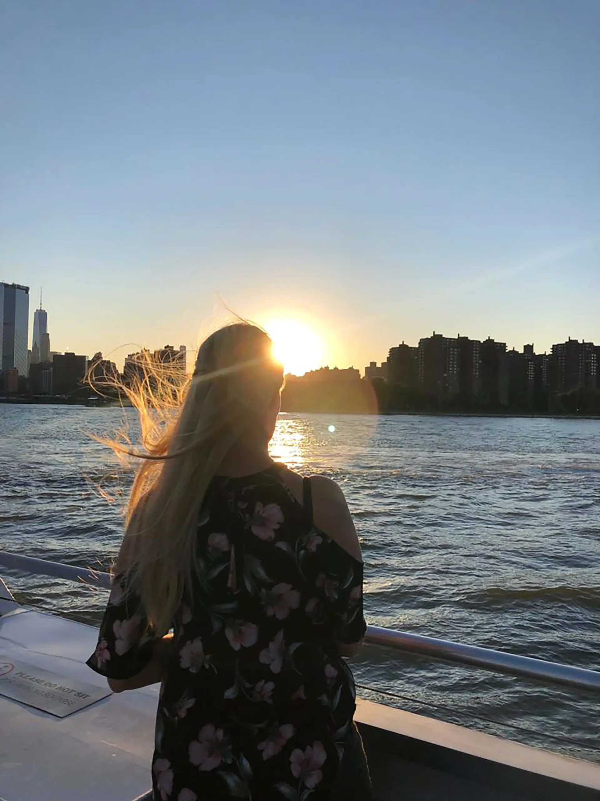 Person auf einem Boot am Hudson River bei Sonnenuntergang mit Skyline von Manhattan