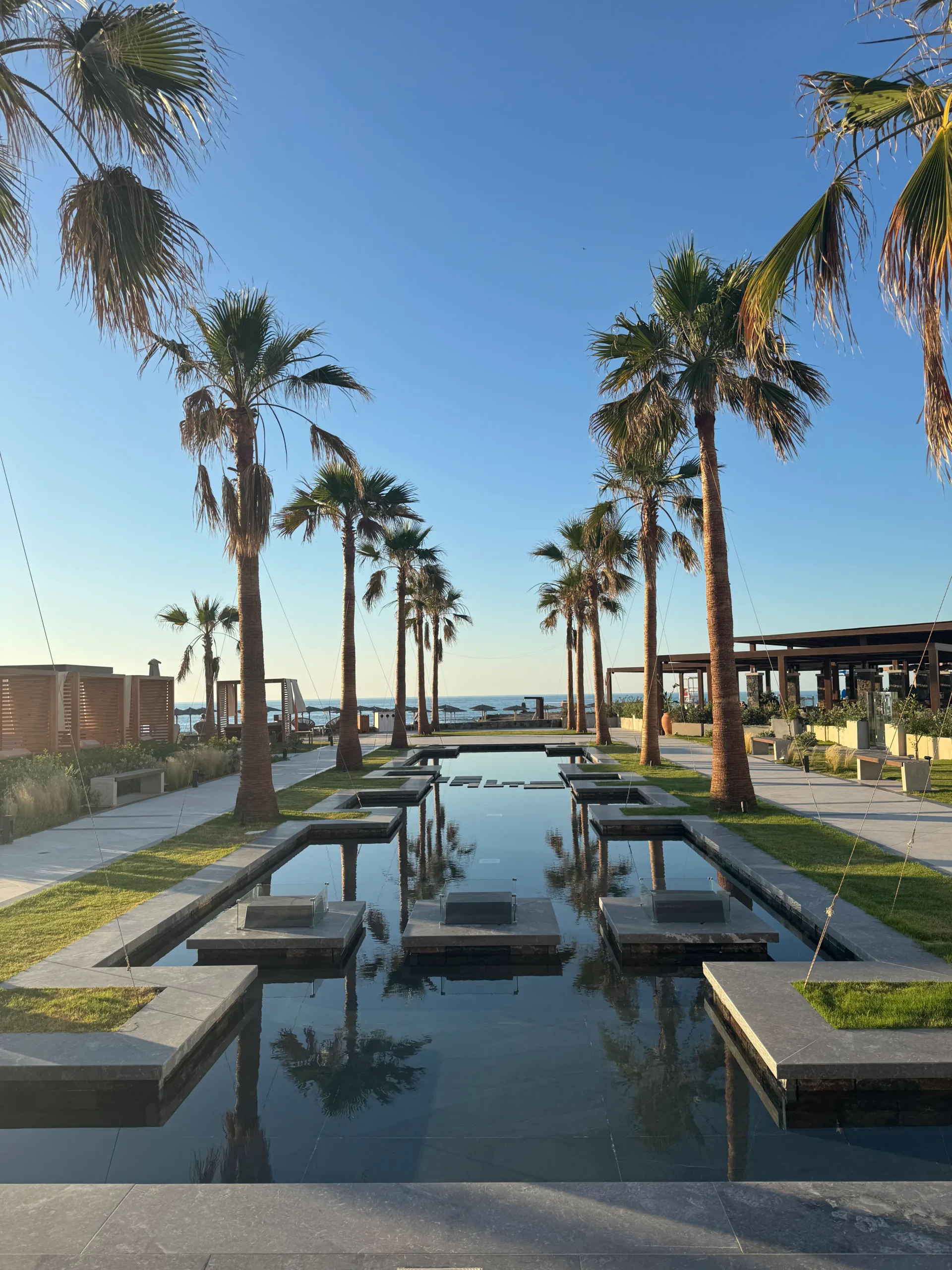 Gartenanlage des allsun Hotel Carolina Sun Beach mit Palmen und geradlinigen Wasserflächen