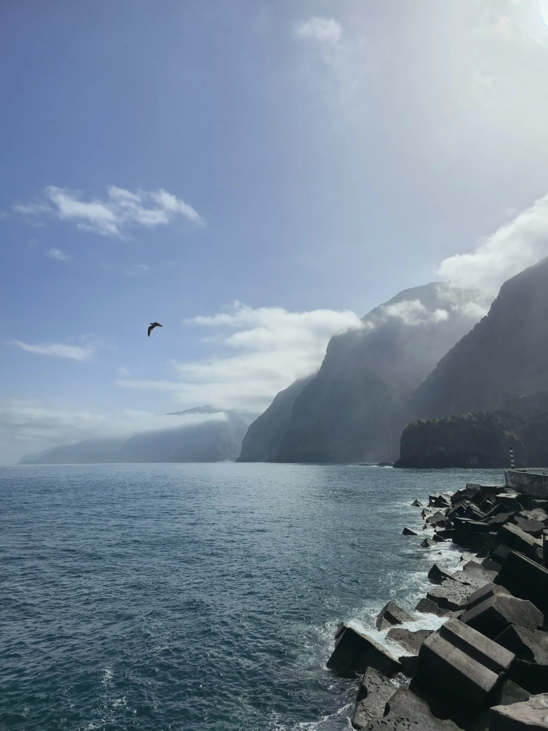 Steile, wolkenverhangene Küste bei Seixal auf Madeira mit Atlantik und Hafenmole
