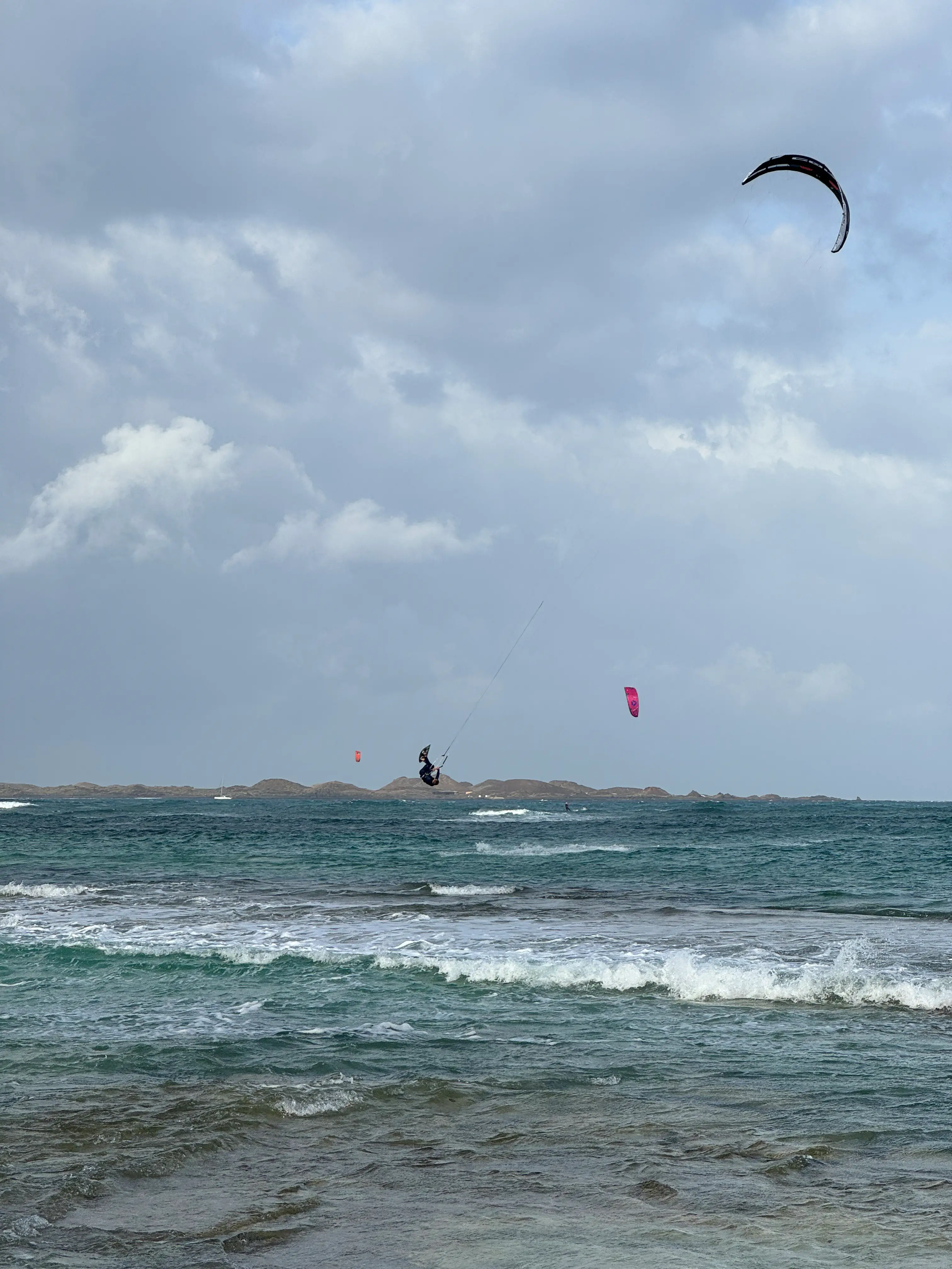 Wind und Wellen vor Corralejo Kitesurfer springt vor der Küste von Corralejo auf Fuerteventura über die Wellen