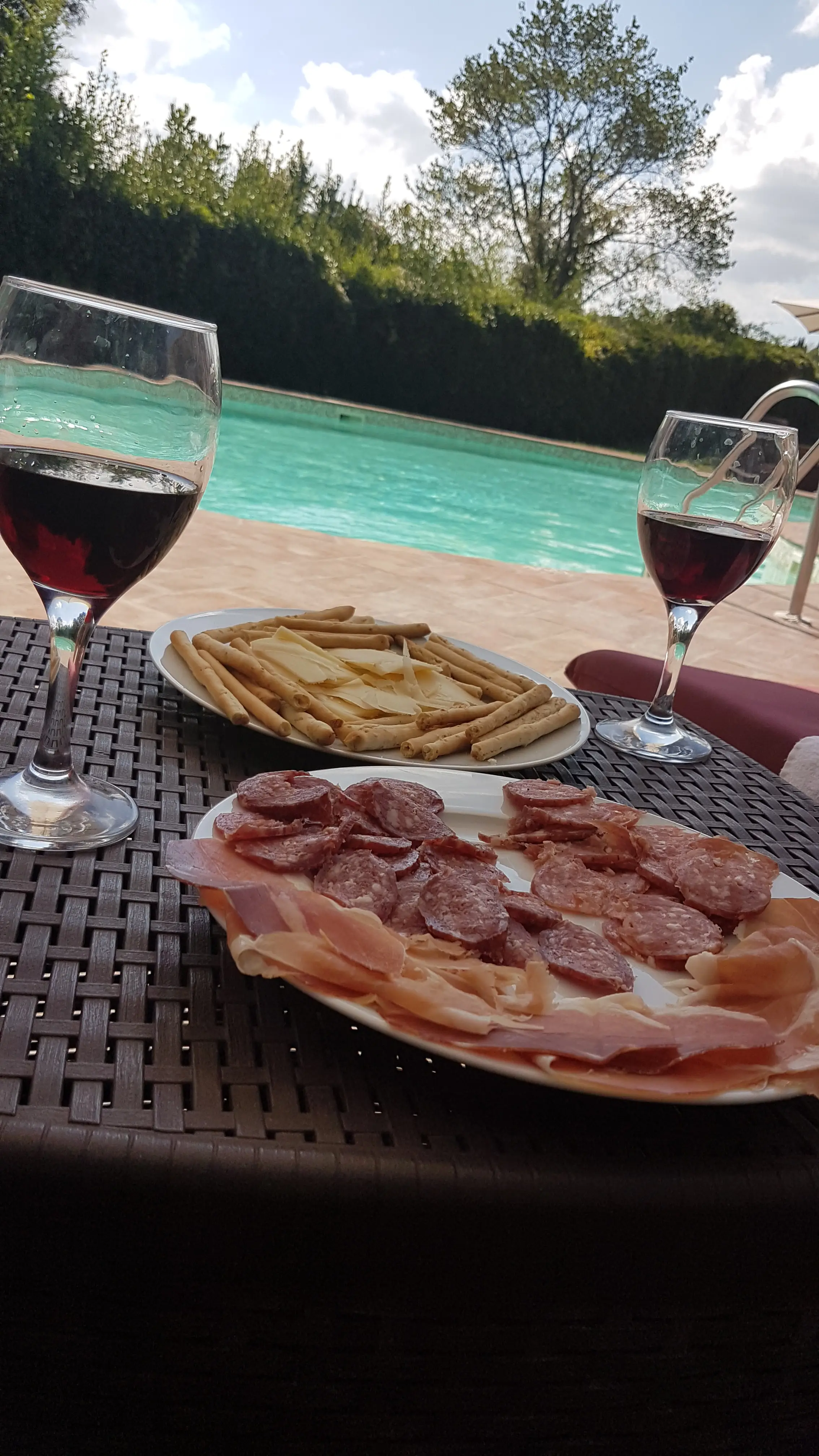 Toskanische Antipasti und Rotwein an einem Pool während einer Rundreise